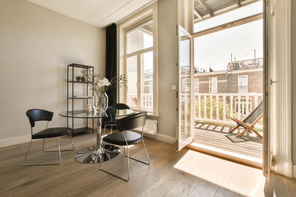a living room with wood flooring and sliding glass doors that open onto the balcony to let in natural light