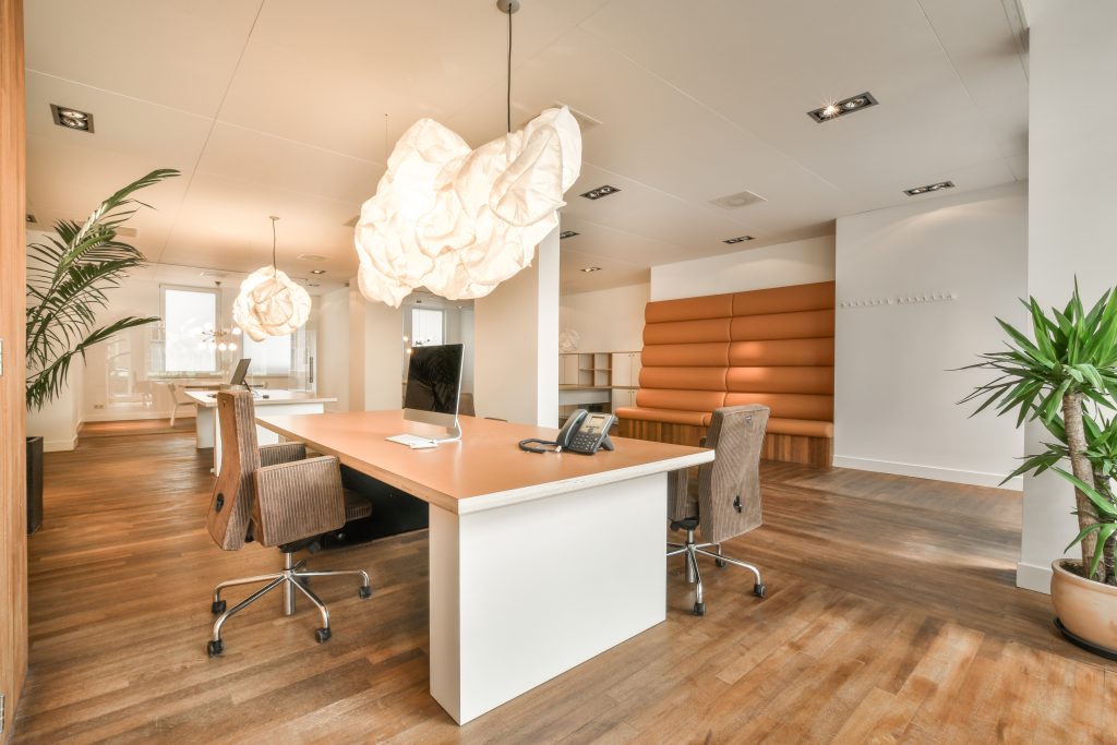 Table with chairs and flowers located near lounge area and kitchen in spacious room of contemporary apartment
