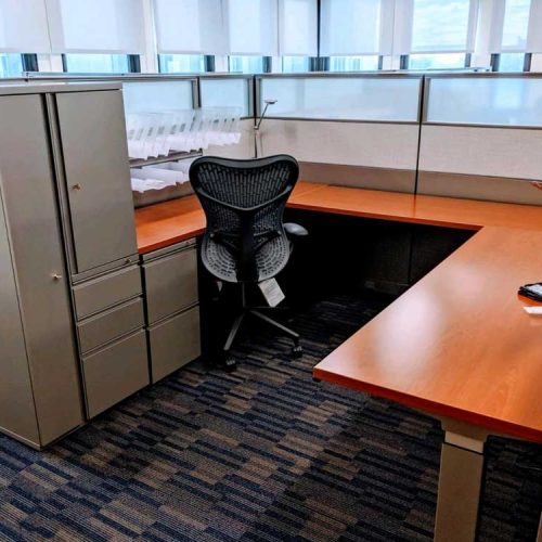 An office cubicle featuring a desk and chair, designed for a professional workspace environment.