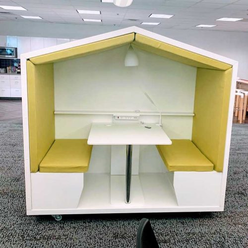 A cozy study nook designed like a small house, featuring yellow cushioned seats, a table, and a lamp for bright lighting.
