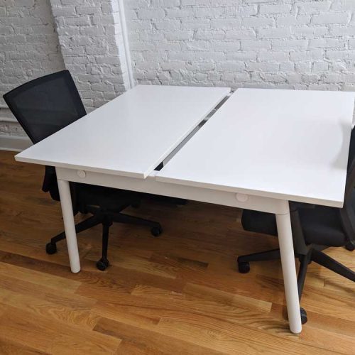 Two white desks accompanied by black chairs in a modern office setting, showcasing a clean and professional workspace.
