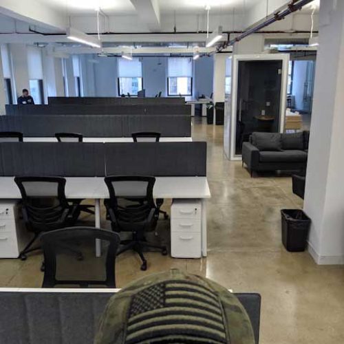 . A man in an office wearing a hat adorned with the American flag, showcasing patriotism in a professional setting.
