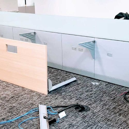 A modern desk featuring a glass partition and a computer setup, creating a sleek and professional workspace.
