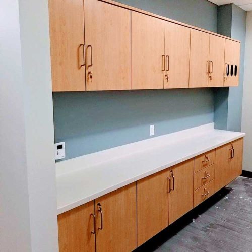 A spacious room featuring numerous cabinets and a long counter, designed for storage and workspace efficiency.