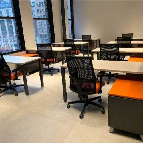 A modern office space featuring multiple desks and ergonomic chairs arranged for productivity and collaboration.